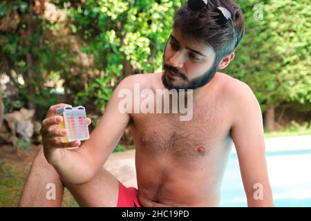 Mann, der den ph- und Cl-Gehalt seines Schwimmbeckens überprüft. Stockfoto