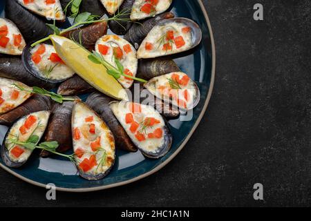 Gebackene Muscheln mit Käse, Lachs, Zitrone und Kräutern Stockfoto