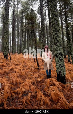 Junge Frau in Schneckenkleidung, die im Winter im Wald steht. Stockfoto