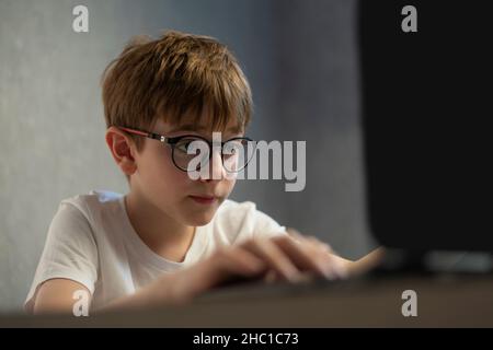 Junge in der Brille spielt begeistert Computerspiele. Teen junge studiert online. Vorbereitung auf Untersuchungen. Stockfoto