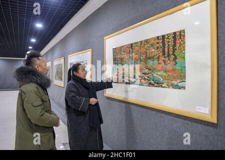 (211222) -- CHANGCHUN, 22. Dezember 2021 (Xinhua) -- Li Baofeng (R) zeigt sich beim Betrachten der Papierschneidearbeiten in Changchun, nordöstlich der Provinz Jilin, am 17. Dezember 2021. Li Baofeng, 56, ist ein Papierschneider in Jilin. Li kombiniert traditionelle Papierschneidetechnik mit Merkmalen verschiedener Malformen wie der chinesischen Malerei, Ölmalerei und Druckgrafik und kreiert ihren eigenen Kunststil. Ihre Werke sind farbenreich und stark im dreidimensionalen Sinn. Die meisten ihrer Kreationen konzentrieren sich auf die klassische chinesische Literatur, Volksbräuche und Landschaften. Eines ihrer Werke "Chinese Red" zeigt eine seri Stockfoto