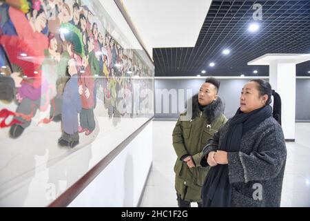 (211222) -- CHANGCHUN, 22. Dezember 2021 (Xinhua) -- Li Baofeng (R) betrachtet die Papierschneidearbeiten in Changchun, nordöstlich der Provinz Jilin, am 17. Dezember 2021. Li Baofeng, 56, ist ein Papierschneider in Jilin. Li kombiniert traditionelle Papierschneidetechnik mit Merkmalen verschiedener Malformen wie der chinesischen Malerei, Ölmalerei und Druckgrafik und kreiert ihren eigenen Kunststil. Ihre Werke sind farbenreich und stark im dreidimensionalen Sinn. Die meisten ihrer Kreationen konzentrieren sich auf die klassische chinesische Literatur, Volksbräuche und Landschaften. Eines ihrer Werke "Chinese Red" zeigt eine Serie von Stori Stockfoto