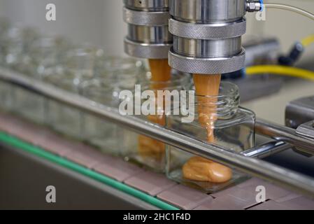 Gläser mit Rahmhonig in einer Verpackungslinie in einer kommerziellen Honigfabrik Stockfoto