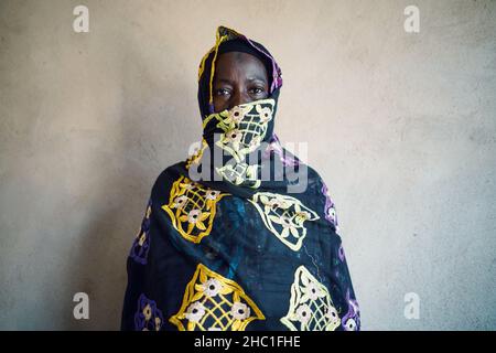 Porträt einer ernsthaften alten schwarzen afrikanischen Dame, die die Kamera anschaut, wobei ihr Gesicht teilweise von einem Schleier bedeckt ist Stockfoto