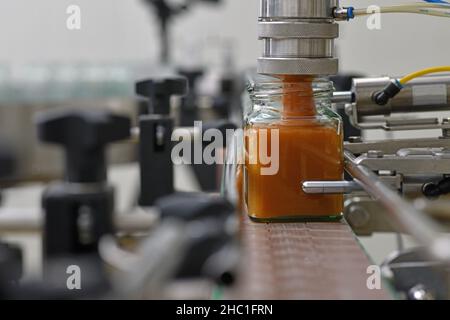 Gläser mit Rahmhonig in einer Verpackungslinie in einer kommerziellen Honigfabrik Stockfoto