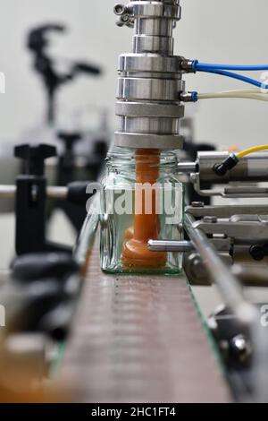 Gläser mit Rahmhonig in einer Verpackungslinie in einer kommerziellen Honigfabrik Stockfoto