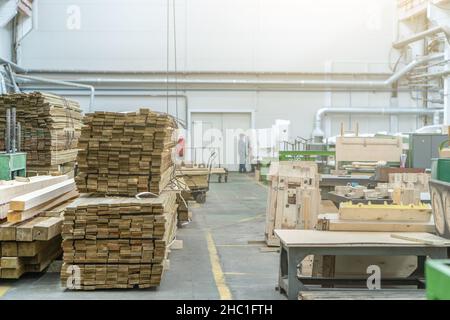 Im Inneren der riesigen holzverarbeitenden Industriefabrik mit Holzstapeln. Stockfoto