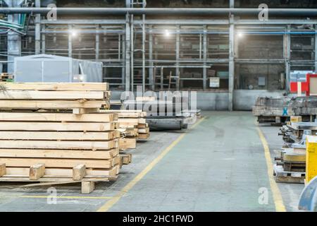 Im Inneren der riesigen holzverarbeitenden Industriefabrik mit Holzstapeln. Stockfoto