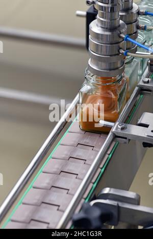 Gläser mit Rahmhonig in einer Verpackungslinie in einer kommerziellen Honigfabrik Stockfoto