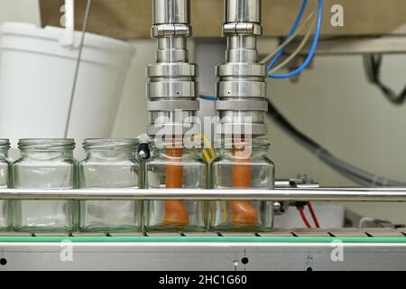 Gläser mit Rahmhonig in einer Verpackungslinie in einer kommerziellen Honigfabrik Stockfoto