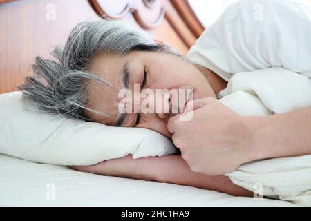 Der ältere asiatische Mann im Schlafzimmer. Stockfoto