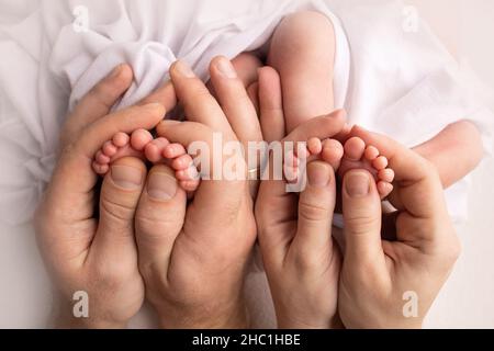 Füße neugeborener Zwillinge. Eltern, Vater Mutter halten neugeborene Zwillinge an den Beinen. Stockfoto