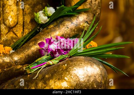 Nahaufnahme einer Meditations-Buddha-Statue mit Orchideenblumen und Lotusblumen in einem buddhistischen Tempel. Stockfoto