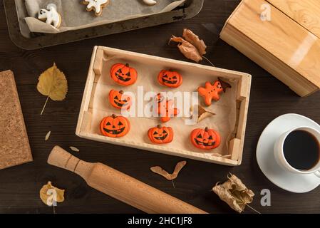 Ingwerkekse für Halloween liegen in Holzform auf dem Tisch. In Kürbisform. Sehr lecker zu essen mit einer Tasse Kaffee Stockfoto