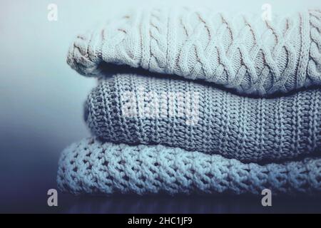Drei warme Wollpullover mit Mustern sind in einem Stapel gestapelt. Schöne Freizeitkleidung für die kalte Wintersaison. Kuschelige Kleidung. Stockfoto