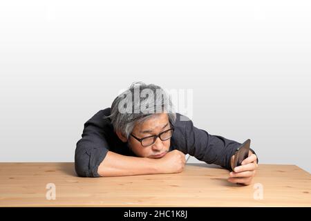 Der ältere asiatische Mann, der an der Rezeption sitzt. Stockfoto