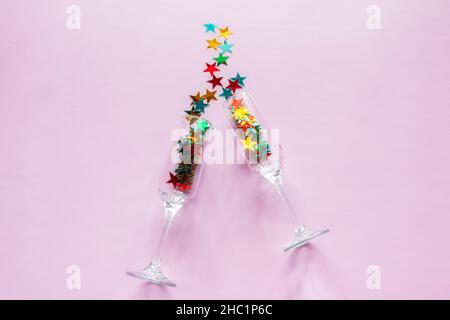 Sektgläser und bunte Konfetti Happy New Year Konzept auf rosa Hintergrund Stockfoto