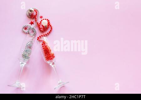 Sektgläser mit Perlen und weihnachtsbaumschmuck auf rosa Hintergrund mit Platz für Text glückliches neues Jahr weihnachten Stockfoto
