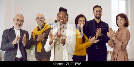 Ein vielfältiges Team von glücklichen, positiven Geschäftsleuten, die Ihnen applaudieren und lächeln Stockfoto