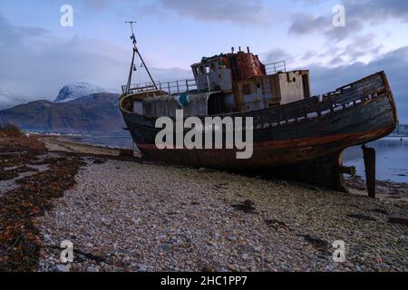 Das Corpach Shipwreck, auch bekannt als das alte Boot von Caol am Loch Eil in der Nähe von Fort William, Schottland, mit dem schneebedeckten BenNevis im Hintergrund. Stockfoto