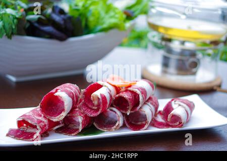 Geschnittene rohe Rinderrollen für heißen Topf auf weißem Teller Stockfoto