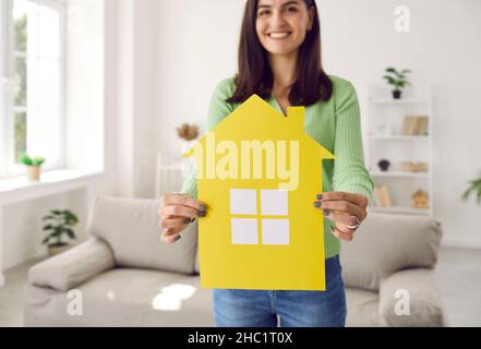 Nahaufnahme des gelben Papiers, Nachbau des Hauses in den Händen einer Frau, die glücklicher Besitzer eines neuen Hauses ist. Stockfoto