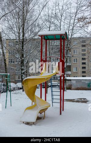 Verschneite Kinderrutsche im Innenhof eines Wohngebietes Stockfoto