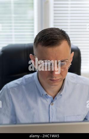 Ein junger Mann mit Brille arbeitet an einem Projekt. Porträt eines Mannes bei der Arbeit an einem Computer. Junger Mann arbeitet an dem Projekt Stockfoto
