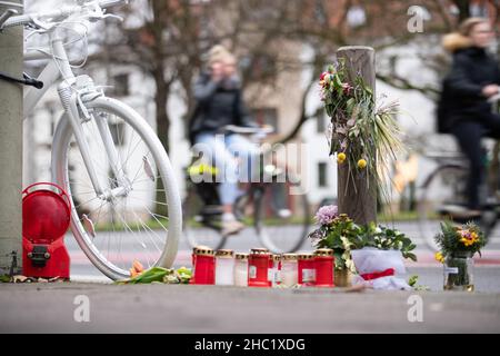 17. Dezember 2021, Niedersachsen, Osnabrück: Ein sogenanntes "Geisterrad" und Trauerkerzen stehen als Mahnmal auf einer belebten Stadtstraße. Mehrere komplett weiß lackierte Fahrräder stehen an Orten, an denen Radfahrer tödliche Unfälle hatten. Foto: Friso Gentsch/dpa Stockfoto