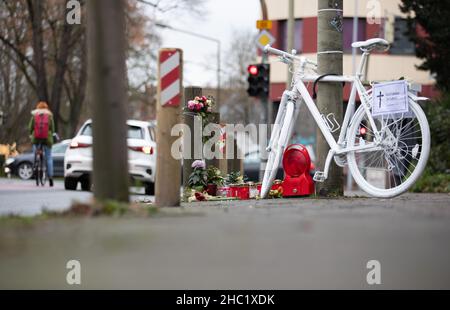 17. Dezember 2021, Niedersachsen, Osnabrück: Ein sogenanntes "Geisterrad" und Trauerkerzen stehen als Mahnmal auf einer belebten Stadtstraße. Mehrere komplett weiß lackierte Fahrräder stehen an Orten, an denen Radfahrer tödliche Unfälle hatten. Foto: Friso Gentsch/dpa Stockfoto