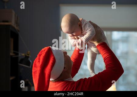 Kaukasischer Großvater in rotem Hut spielt mit Enkelin zu Hause selebrating Weihnachten Stockfoto