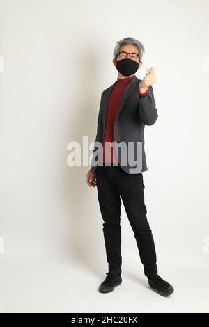Der ältere asiatische Mann im eleganten Casual auf dem weißen Hintergrund stehend. Stockfoto