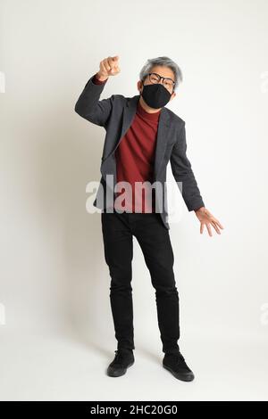 Der ältere asiatische Mann im eleganten Casual auf dem weißen Hintergrund stehend. Stockfoto