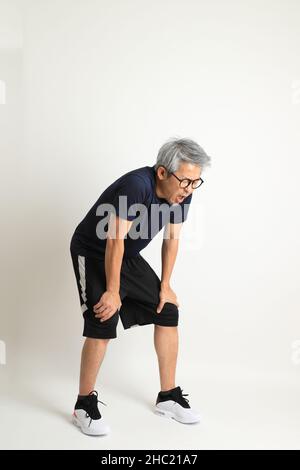 Der asiatische Senioren mit Sportkleidung auf weißem Hintergrund. Stockfoto