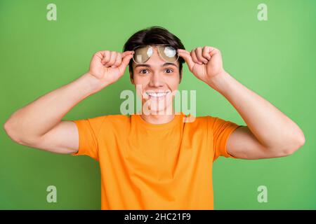 Foto von glücklich fröhlich jungen positiven Mann tragen Sonnenschutzglas gute Laune Nachrichten isoliert auf grünem Hintergrund Stockfoto