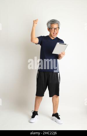 Der asiatische Senioren mit Sportkleidung auf weißem Hintergrund. Stockfoto
