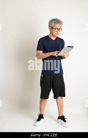 Der asiatische Senioren mit Sportkleidung auf weißem Hintergrund. Stockfoto