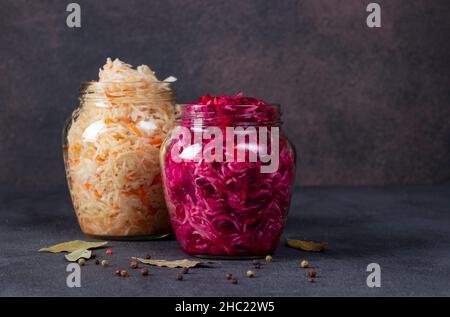 Hausgemachtes Sauerkraut mit Karotte und Rote Beete in Gläsern ein dunkelgrauer Tisch. Fermentierte Lebensmittel Stockfoto