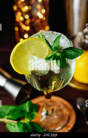 Frischer Mojito-Cocktail mit Zitrone, Minze und Eis im Weinglas auf dunklem Hintergrund. Sommerliche kalte Getränke und Cocktails. Nahaufnahme aus einem hohen Winkel Stockfoto