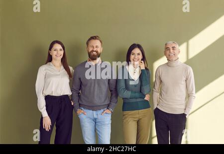 Gruppenporträt von vier glücklichen Geschäftsleuten in eleganter Freizeitkleidung, die im Studio stehen Stockfoto