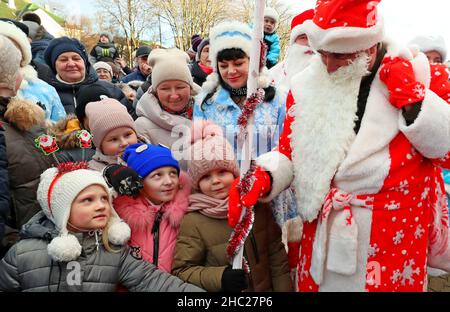 (211220) -- MINSK, 20. Dezember 2021 (Xinhua) -- Kinder und Menschen, die in den Kostümen von Pater Frost und Snow Maiden gekleidet sind, werden am 19. Dezember 2021 in Minsk, Weißrussland, bei einer Neujahrsparade gesehen. (Foto von Henadz Zhinkov/Xinhua) Stockfoto