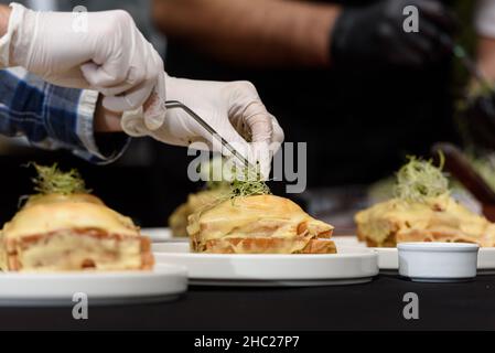 Francesinha, traditionelles portugiesisches Sandwich, ursprünglich aus Porto. Konzept der nationalen Küche. Der Küchenchef bereitet ein Gericht im Restaurant zu Stockfoto