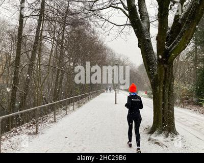 Hamburg, Deutschland. 23rd Dez 2021. Ein Läufer joggt im leichten Schnee entlang eines Kanals. Quelle: Thomas Müller/dpa/Alamy Live News Stockfoto