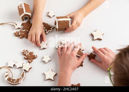 Kinder bereiten sich auf Weihnachten vor. Lebkuchenkekse in den Händen der Kinder. Draufsicht. Stockfoto