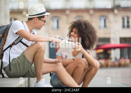 Junges Paar saß auf einer Treppe mit einer Touristenkarte Stockfoto