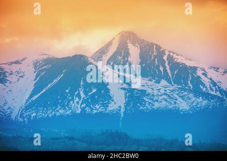 Wunderschöne schneebedeckte Berge vor dem Hintergrund eines Sonnenuntergangs Himmel mit dramatischen Wolken. Liptovsky Sea Region, Hohe Tatra, Slowakische Republik, Europa Stockfoto