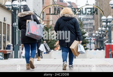 Hamburg, Deutschland. 23rd Dez 2021. Passanten laufen am Tag vor Weihnachten mit Einkaufstaschen durch die Innenstadt. Quelle: Markus Scholz/dpa/Alamy Live News Stockfoto