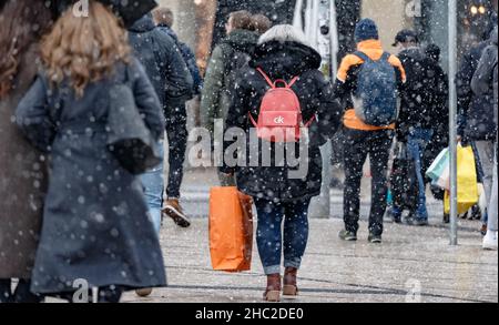 Hamburg, Deutschland. 23rd Dez 2021. Passanten laufen am Vorweihnachtstag mit Einkaufstaschen durch die Innenstadt bei leichtem Schneefall. Quelle: Markus Scholz/dpa/Alamy Live News Stockfoto