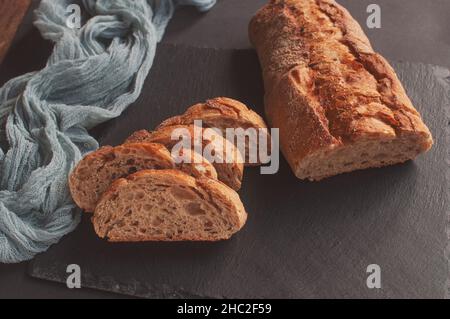 Handgemachtes französisches Brot Selection Baguette mit grauer Gaze-Tischdecke auf schwarzem Hintergrund Stockfoto