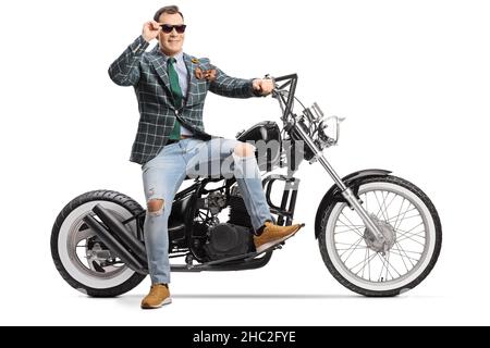 Mann in stilvollem Anzug und Jeans sitzt auf einem Chopper-Motorrad und trägt Sonnenbrille isoliert auf weißem Hintergrund Stockfoto